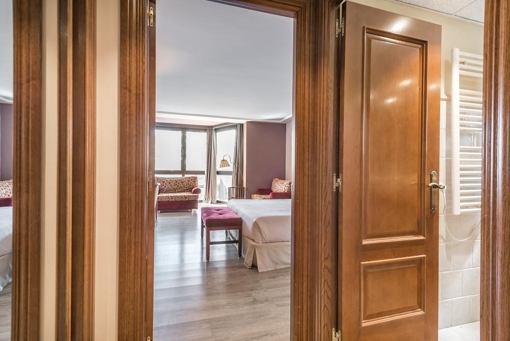 una puerta de madera que conduce a una habitación con una cama y una silla