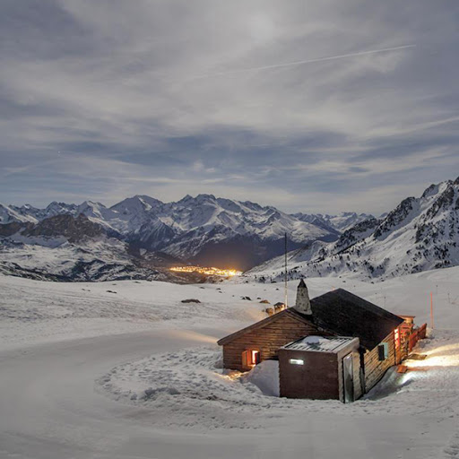 une cabane en bois dans la neige avec des montagnes en arrière-plan