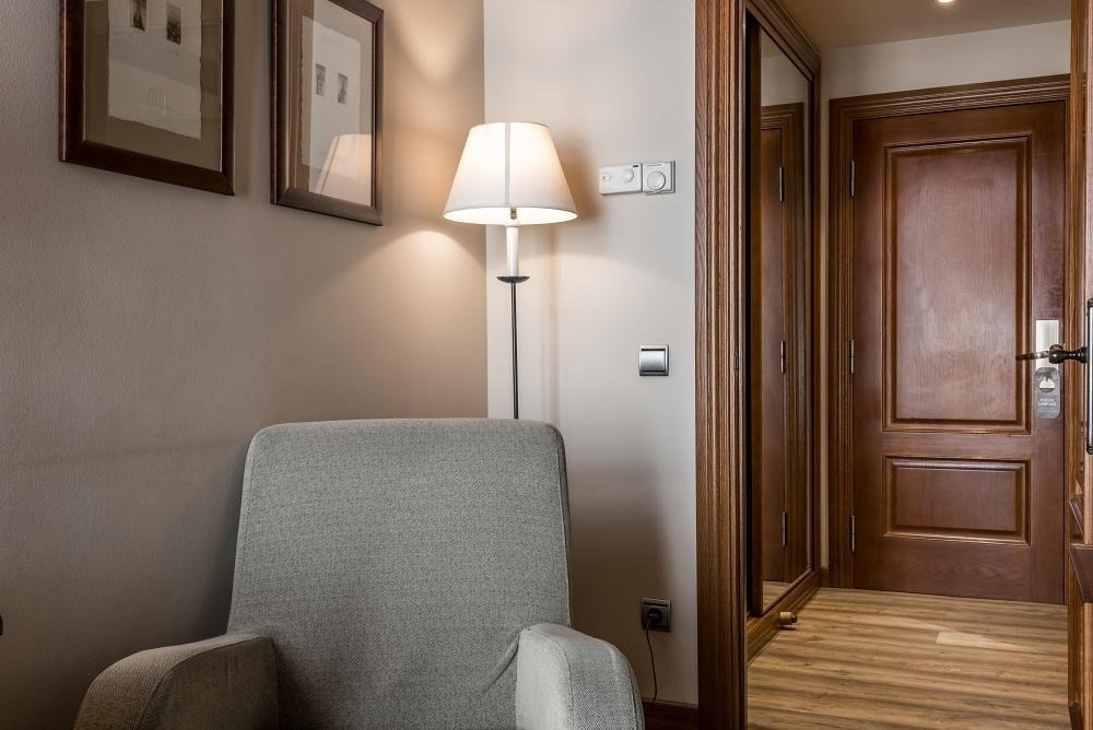 una silla junto a una lámpara y un espejo en una habitación