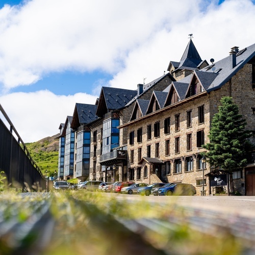 un grand bâtiment en pierre avec un toit en ardoise et des voitures garées devant