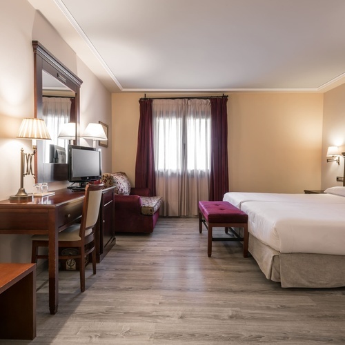 a hotel room with two beds a desk and a television