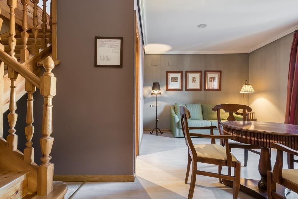 una escalera de madera conduce a una habitación con una mesa y sillas