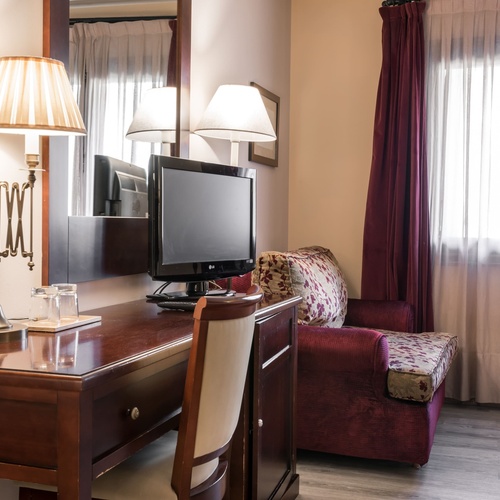 a hotel room with a desk a chair and a television