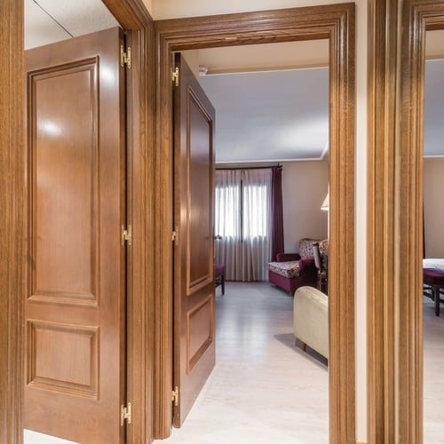 une porte en bois s'ouvre sur une chambre avec un canapé