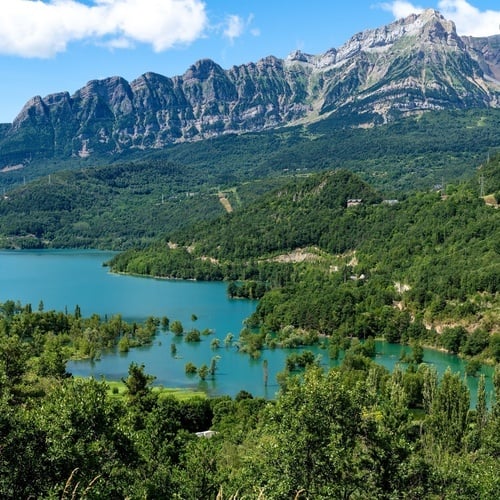 un lago rodeado de árboles y montañas en un día soleado