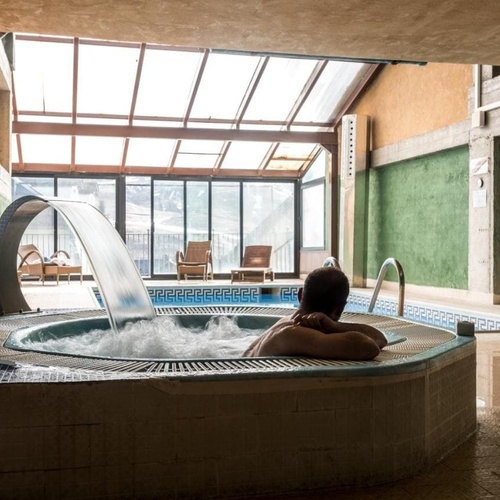 a man sits in a hot tub with a waterfall coming out of it