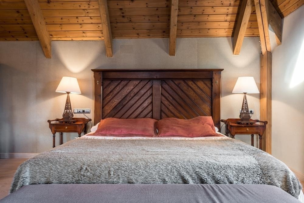 una cama con dos mesitas de noche y una cabecera de madera