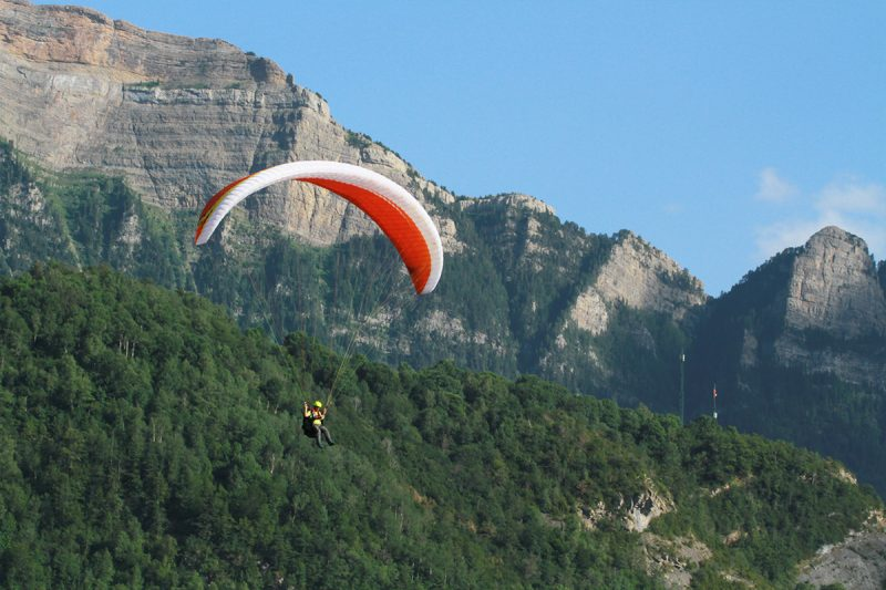 un hombre y una mujer están volando en parapente sobre un lago .