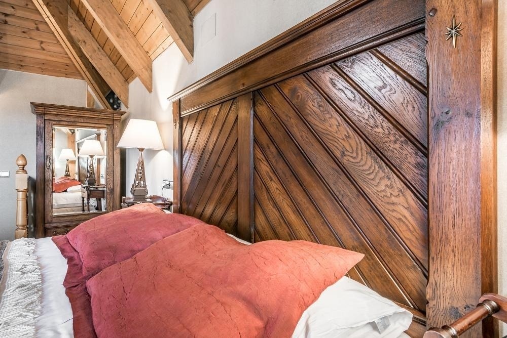 una cama con una cabecera de madera y almohadas rojas