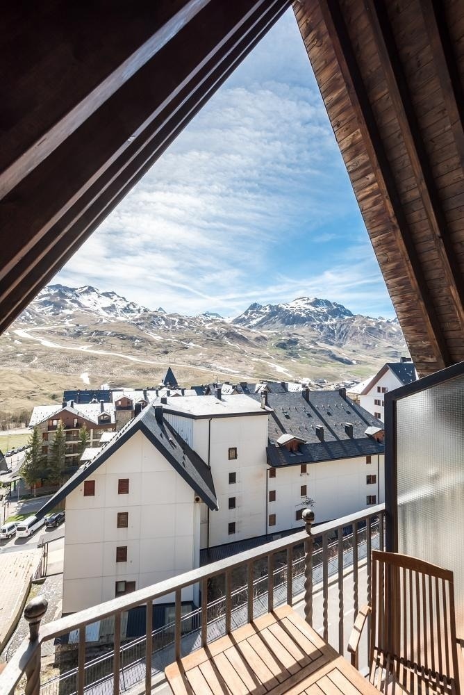 una vista de las montañas desde un balcón con una mesa y sillas