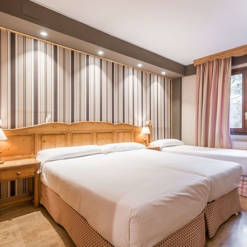 a hotel room with two beds and striped wallpaper