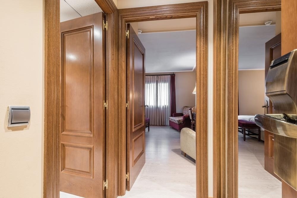 una puerta de madera se abre a un pasillo que conduce a un dormitorio