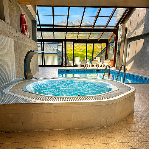Indoor hot tub with a view of mountains and a swimming pool at SNO: Villa de Sallent 4*.