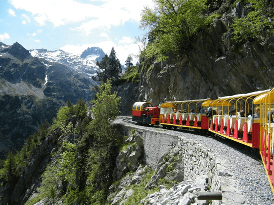 un tren rojo y amarillo conduce por una carretera de montaña