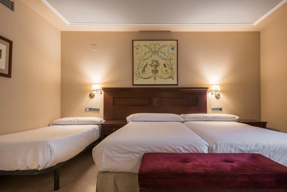 una habitación con tres camas y una pintura en la pared