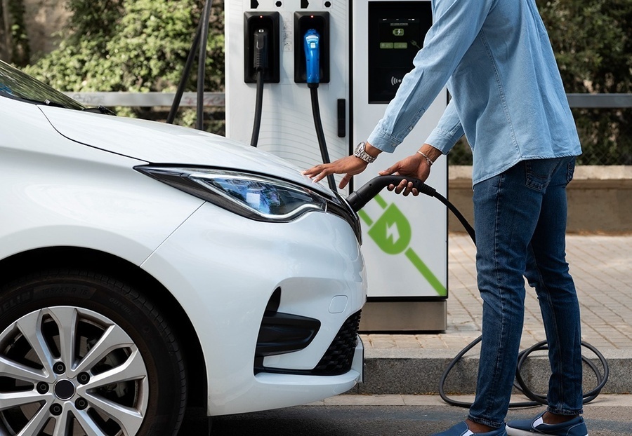 un hombre está cargando un coche eléctrico en una estación de carga