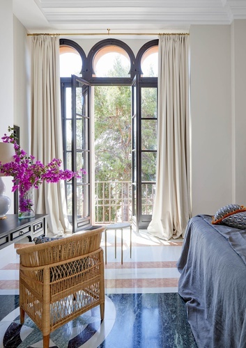 a bedroom with a wicker chair and a large window