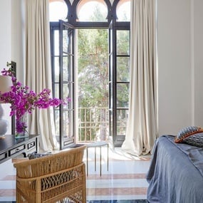 a bedroom with a wicker chair and a large window