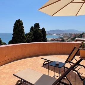 eine Terrasse mit Liegestühlen und einem Sonnenschirm mit Blick auf den Ozean