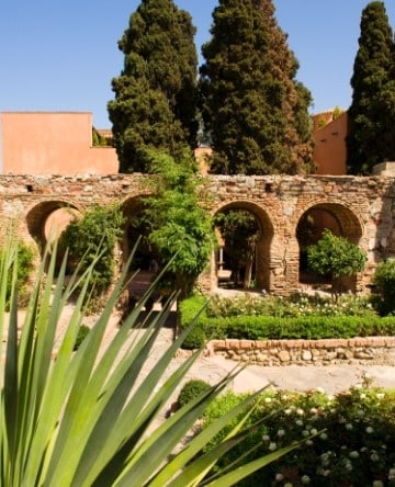 ein Garten mit Bäumen und einem Steingebäude im Hintergrund