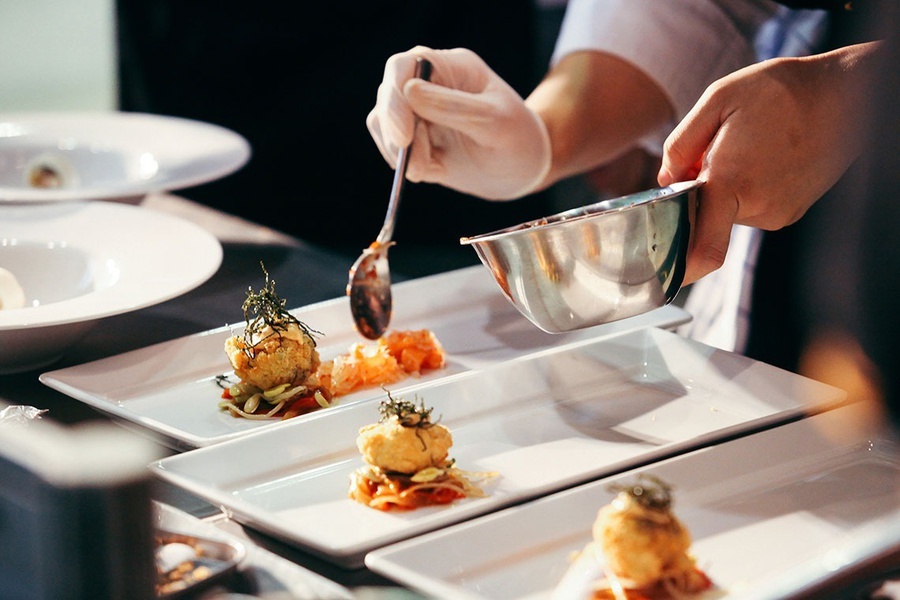 a chef prepares a plate of food with a spoon