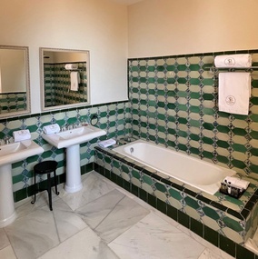 un baño con azulejos verdes y blancos y una bañera