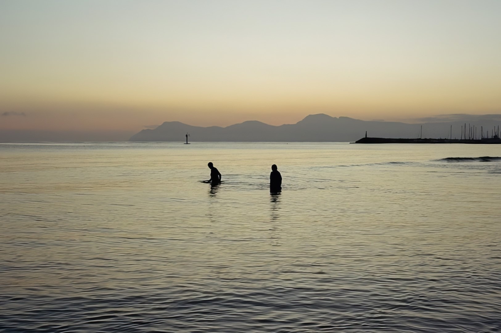 two people in the water with mountains in the background