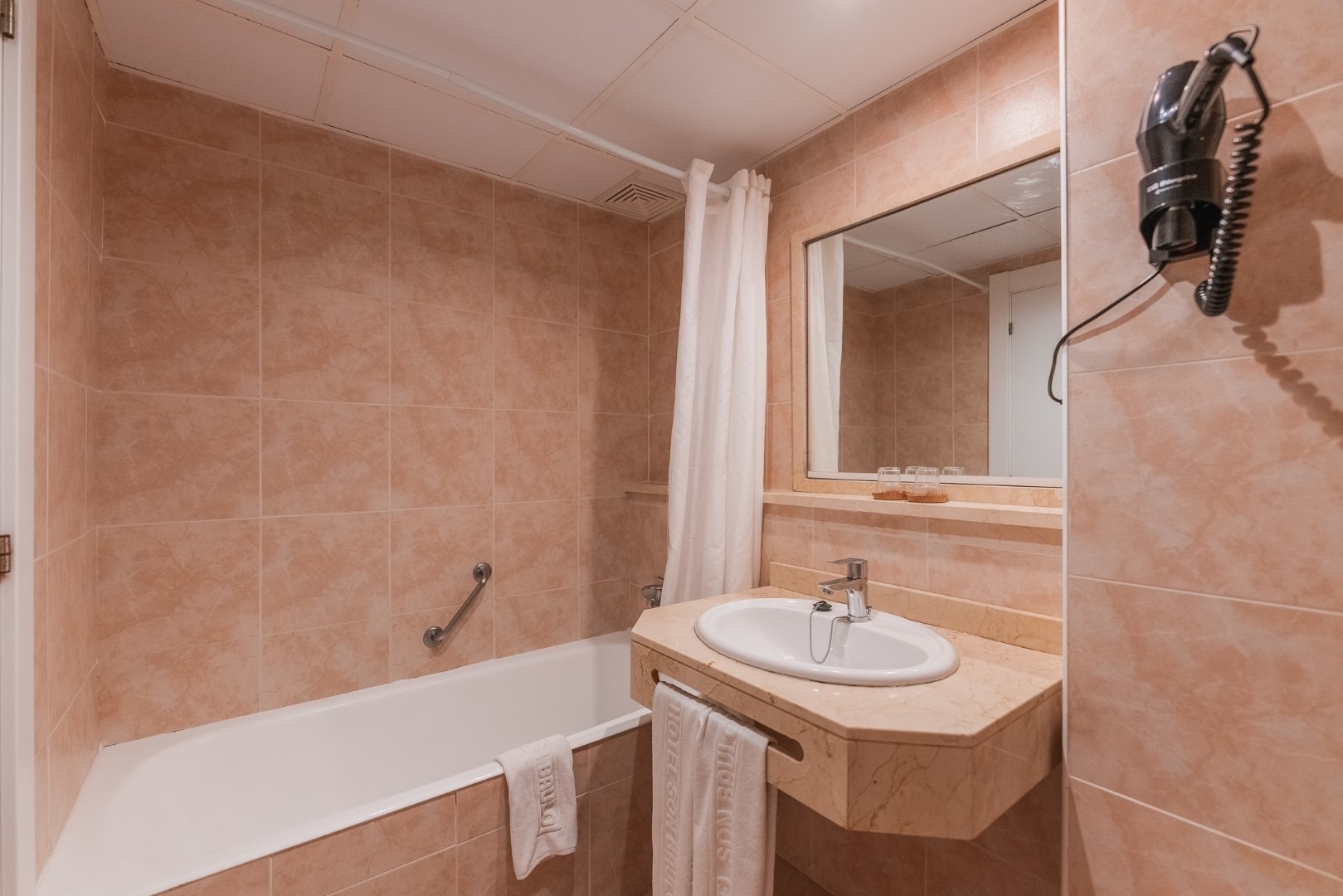 a bathroom with a sink and a towel that says ' hotel ' on it