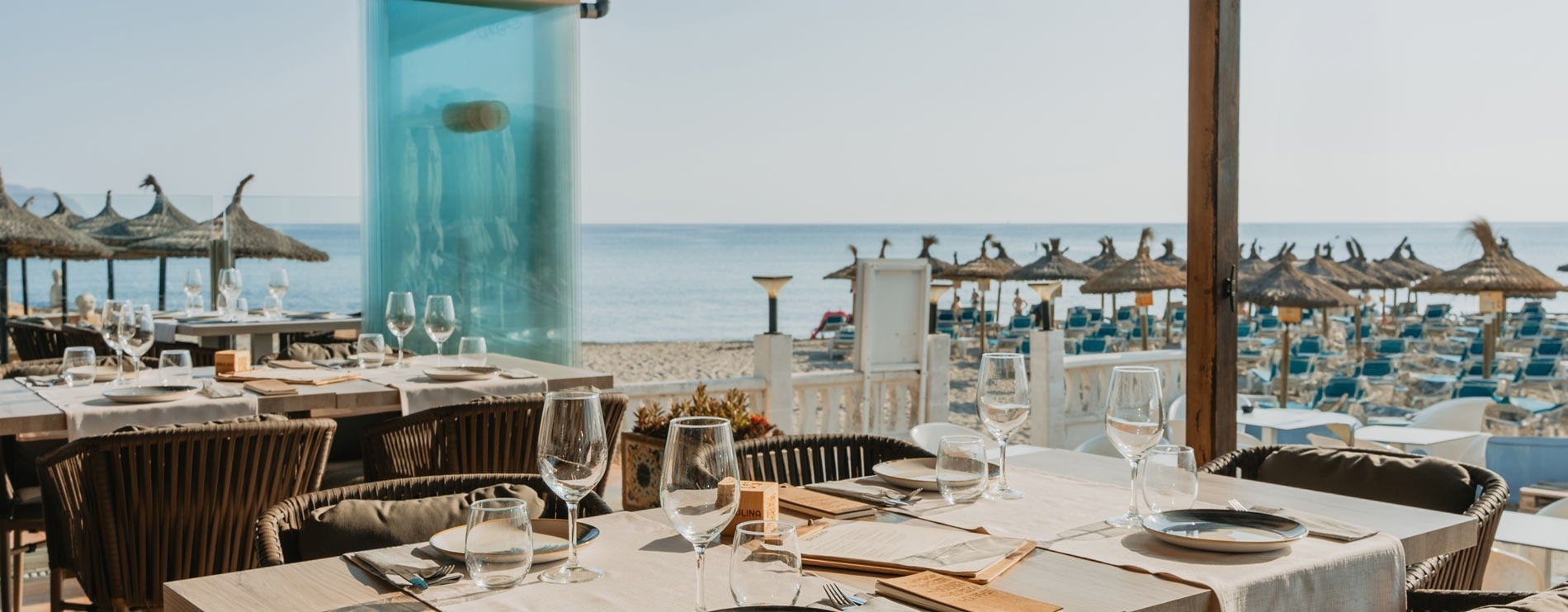ein Restaurant mit Blick auf den Ozean und einem Tisch mit Gläsern und Tellern