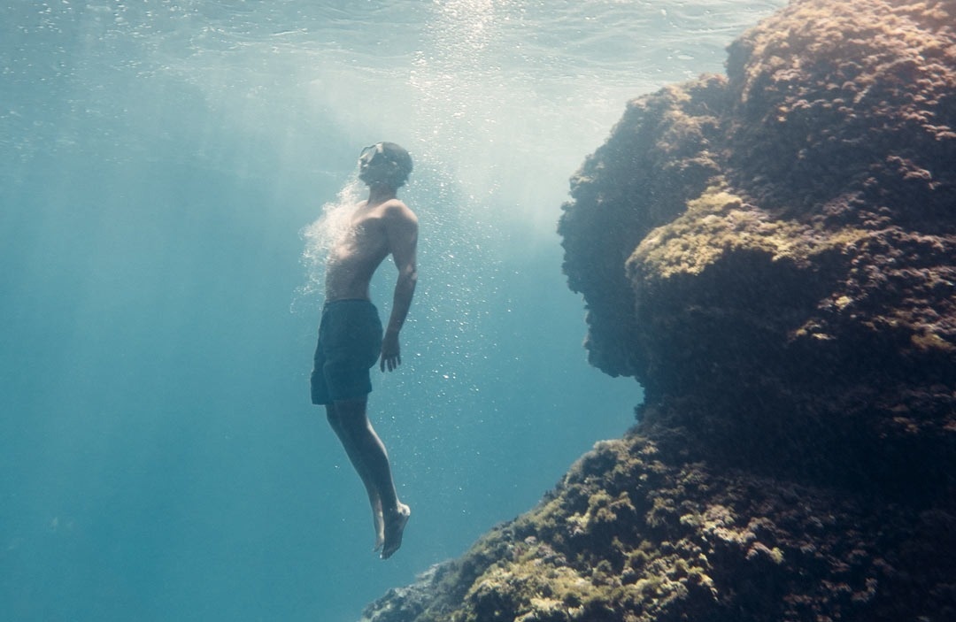 un hombre sin camisa nada en el océano