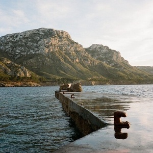 un muelle con una montaña al fondo y la letra e en el agua