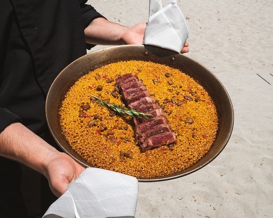 ein Mann hält eine Pfanne mit Reis und Fleisch darin