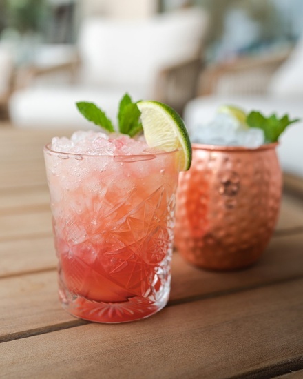 ein Glas mit einer Limettenscheibe darauf sitzt auf einem Holztisch