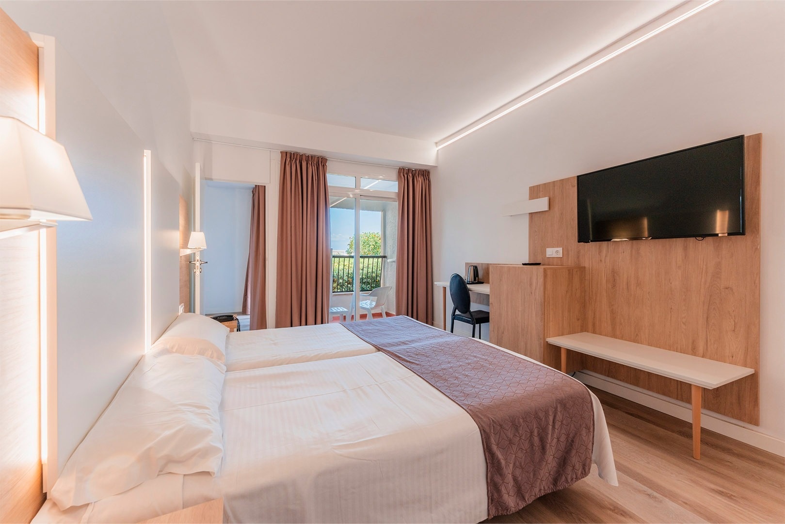 a hotel room with two beds a desk and a television