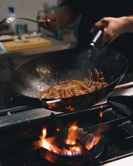 eine Person kocht Essen in einer Pfanne auf einem Herd
