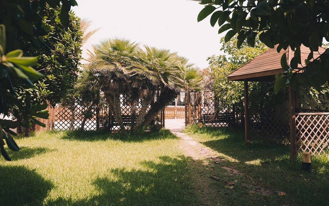 a wooden gazebo sits in the middle of a lush green garden