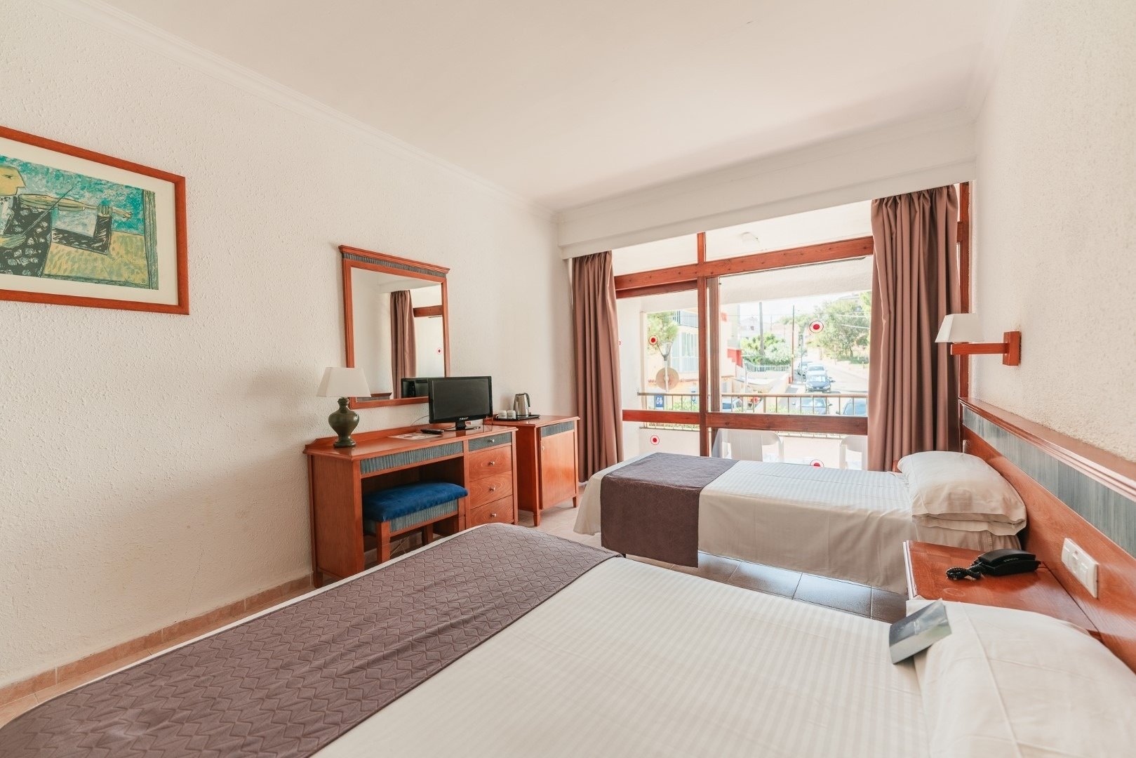 a hotel room with two beds a desk and a television