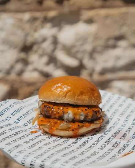 Eine Person nimmt einen Hamburger mit Pommes frites aus einem Korb