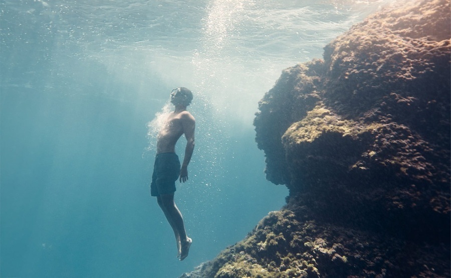 un hombre sin camisa nada en el océano