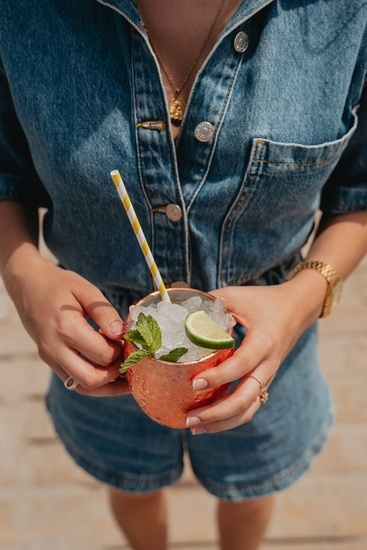 Eine Frau hält einen Drink mit Eis und Limetten in ihren Händen