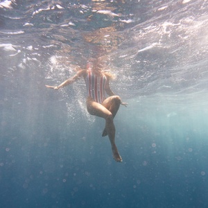 eine Frau in einem gestreiften Badeanzug schwimmt unter Wasser