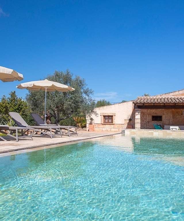 a swimming pool surrounded by chairs and umbrellas on a sunny day