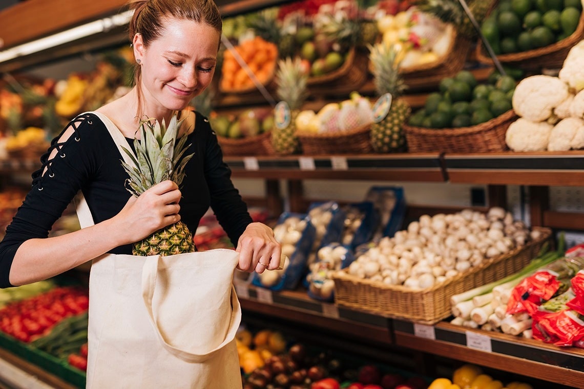 een vrouw houdt een ananas in haar handtas in een supermarkt