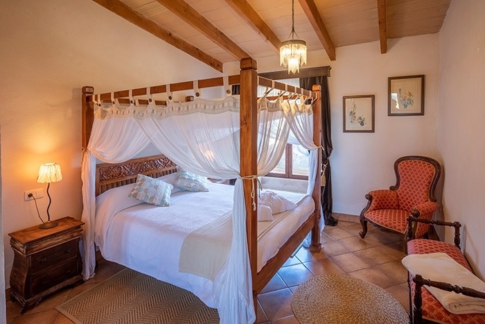 een slaapkamer met een hemelbed en een rode stoel