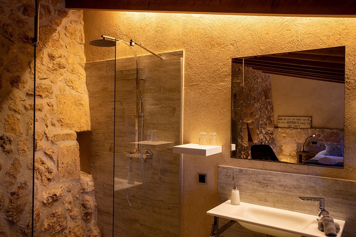 een badkamer met een wastafel en een douche en een spiegel