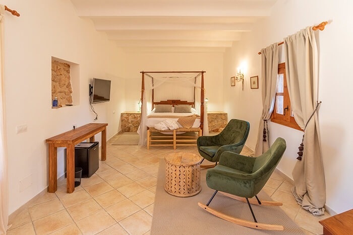 een slaapkamer met een hemelbed en twee schommelstoelen