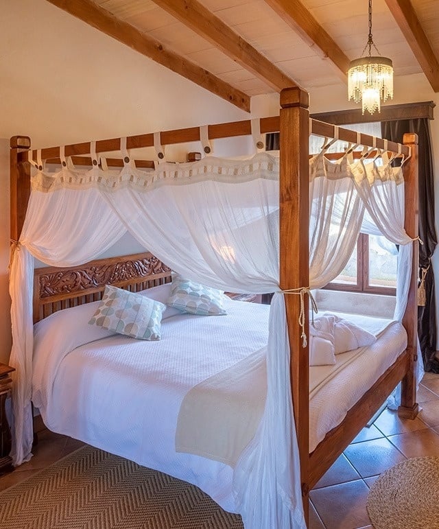 una cama con dosel y cortinas blancas en una habitación
