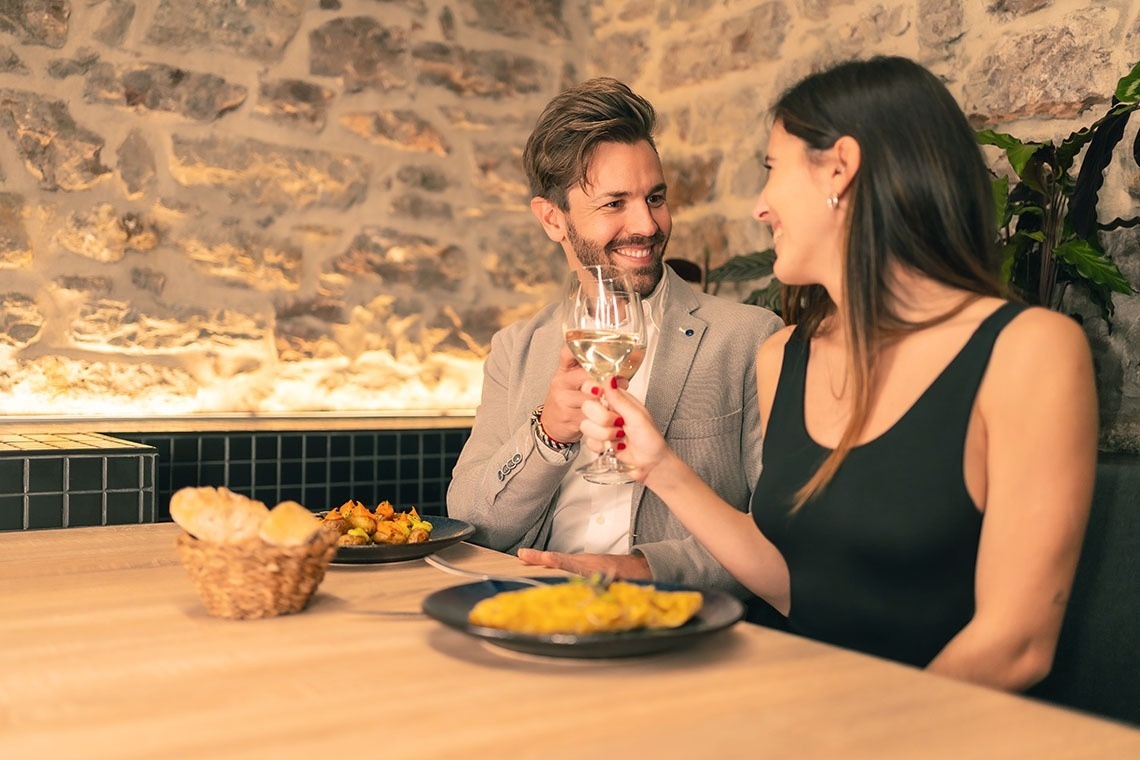 un hombre y una mujer sostienen copas de vino en un restaurante