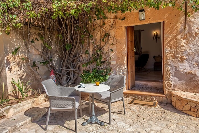 een tafel en stoelen op een stenen terras naast een deur