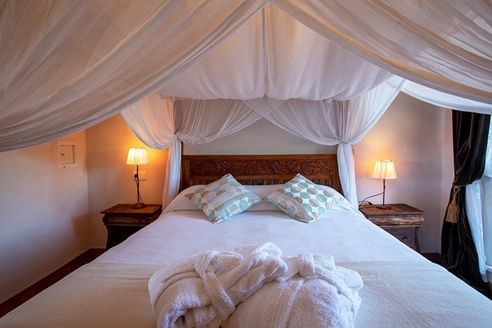 een bed met een baldakijn en een badjas bovenop